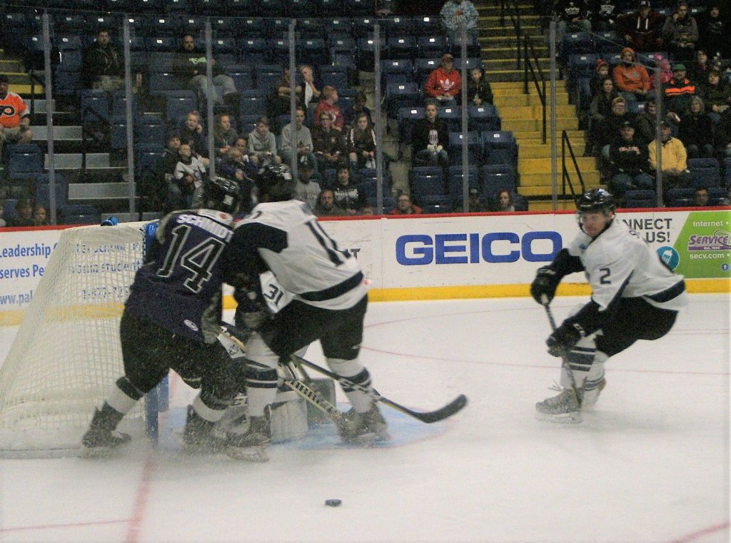 Through the ice spray Jacksonville’s Scott Savage heads to clear out the loose puck from the Icemen zone